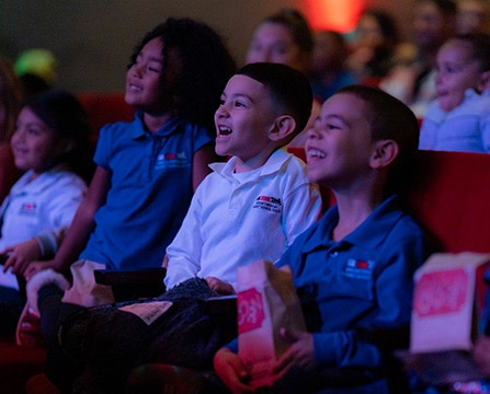 children in theater seats smiling