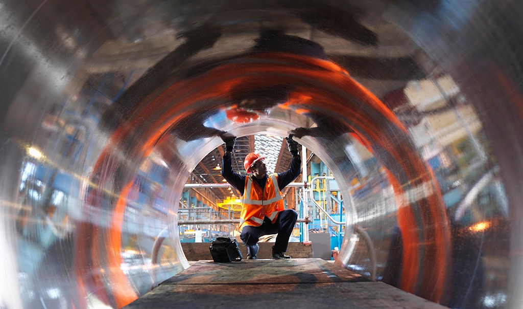 looking through a metal pipe towards a worker