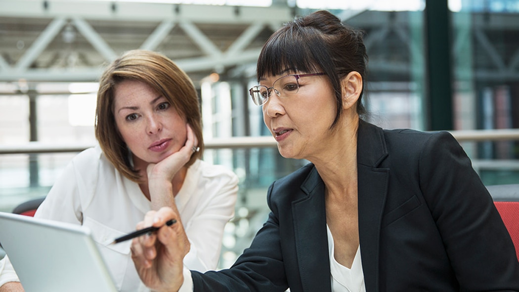 Two women look at a laptop